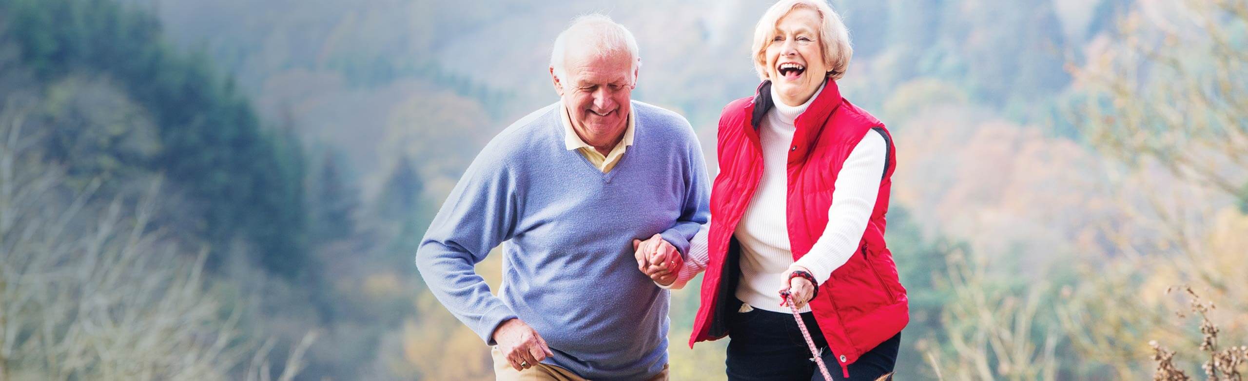 Man and woman walking outside while holding hands and laughing